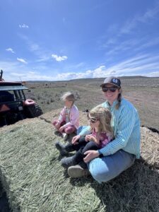 Feeding cows on a feed wagon with kids.
