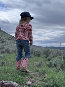 Young girl overlooking a sagebrush-covered rangeland, symbolizing the next generation of ranchers and land stewards.